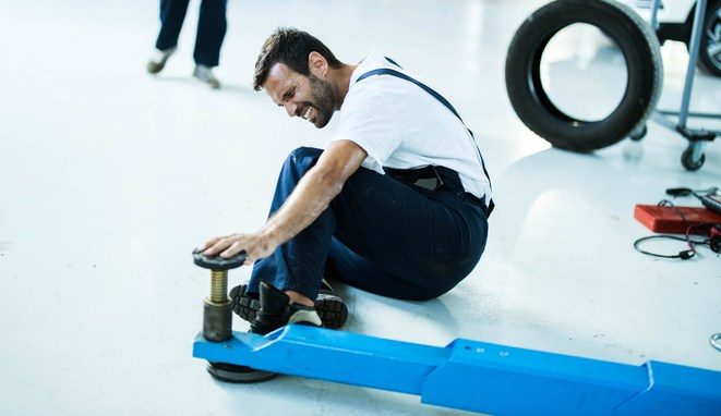 Unfortunate repairman hurt his feet in auto repair shop.