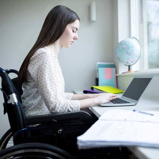 Una alumna en silla de ruedas, delante de su ordenador