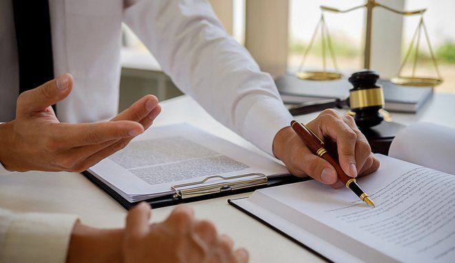 Justice and Law concept. Legal counsel presents to the client a signed contract with gavel and legal law or legal having team meeting at law firm in background
