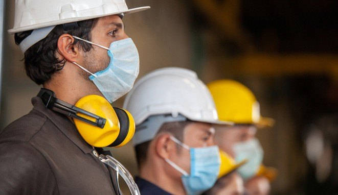 Workers wear protective face masks for safety in machine industrial factory.
