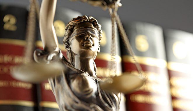 Statue Of Lady Justice In Front Of Row Of Law Books