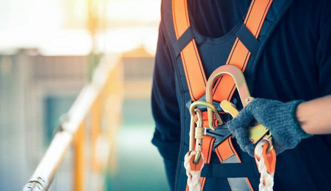 Construction worker wearing safety harness and safety line working at high place