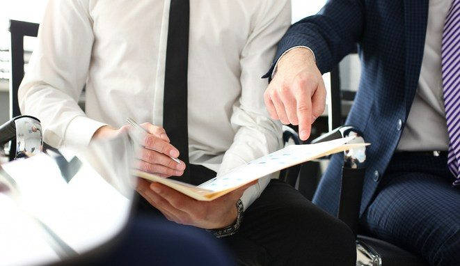 Male hand in suit and tie showing something important in tax interview document