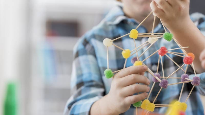 Niño creando ADN con gominolas. Pedagogía Reggio Emilia.