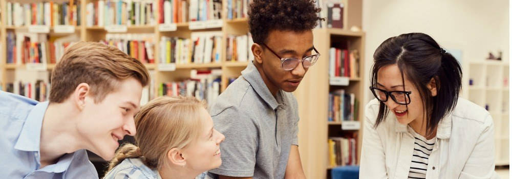 Educación inclusiva. Grupo de alumnos jóvenes mulitculturales hablando en una biblioteca