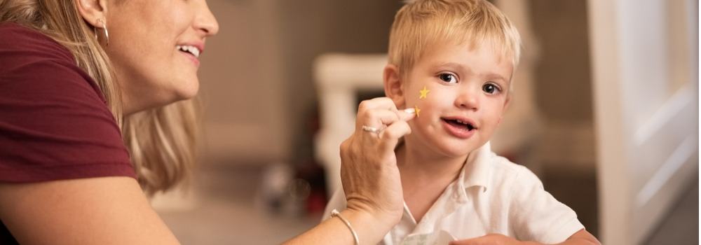 Salud, Psicología, Condicionamiento operante. Una profesora pone una pegatina de estrella en la mejilla de un niño.