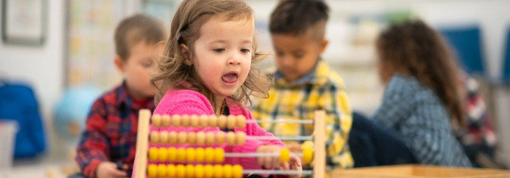 Educación infantil, matemámticas. Niña preescolar jugando con ábaco.