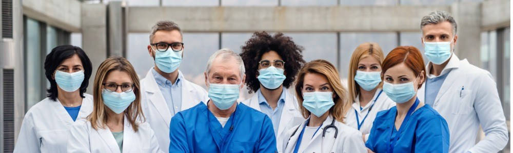 Dirección y Gestión Sanitaria; un grupo de sanitarios mirando hacia la cámara en frente del hospital