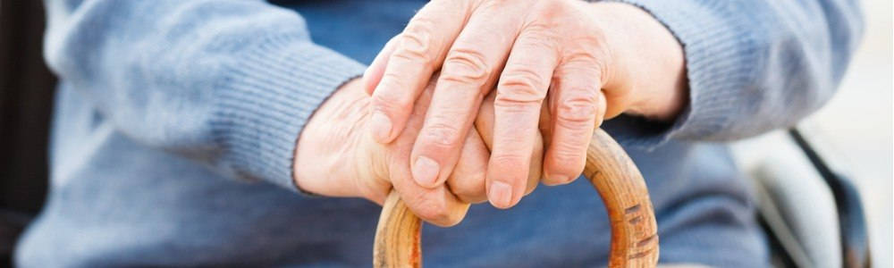 atención de las personas en situación de dependencia; manos de un anciano apoyadas en un bastón