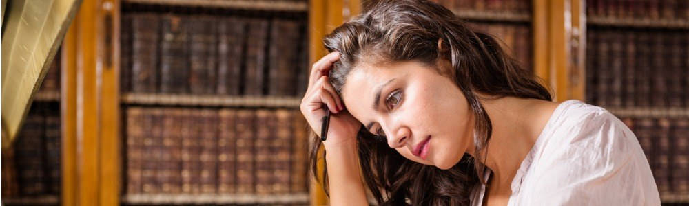 Estrés y ansiedad en el aula; mujer jóven estresada en una biblioteca
