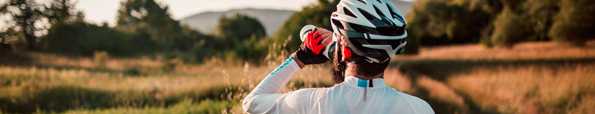 hidratación en el deporte; un ciclista descansa para en el campo para beber agua