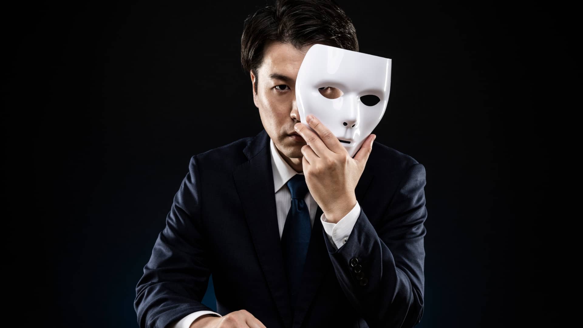 Persona que se esconde detrás de una máscara, representando el síndrome del impostor