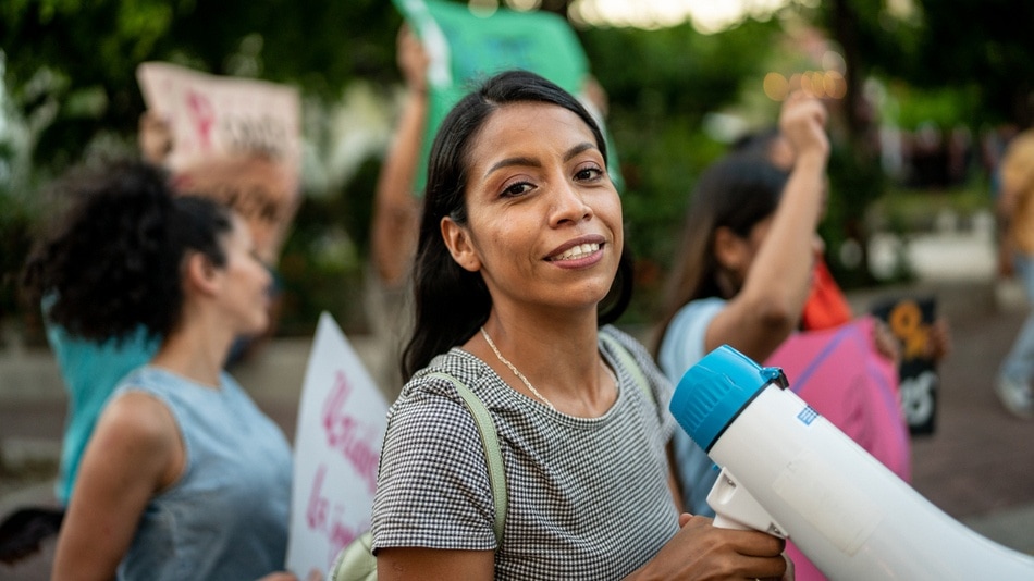 Mujer joven con un megáfono en una protesta en la calle