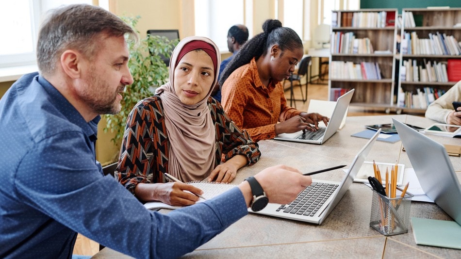 Trabajador social ayudando a un inmigrante en una biblioteca