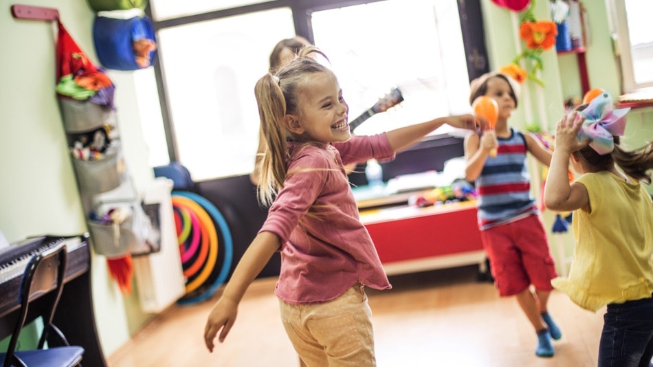 Niños en clase bailando y jugando con instrumentos musicales