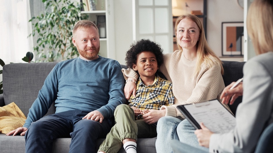 Trabajadora social hablando con una familia en el salón de la casa