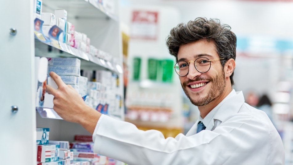 Farmacéutico cogiendo un medicamento de un stand