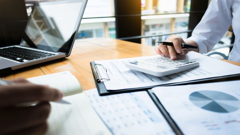 Personas haciendo una auditoria en una oficina con un ordenador, calculadora e informes