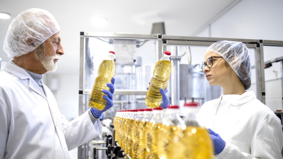 Trabajadores de una fabrica inspeccionando botellas de aceite