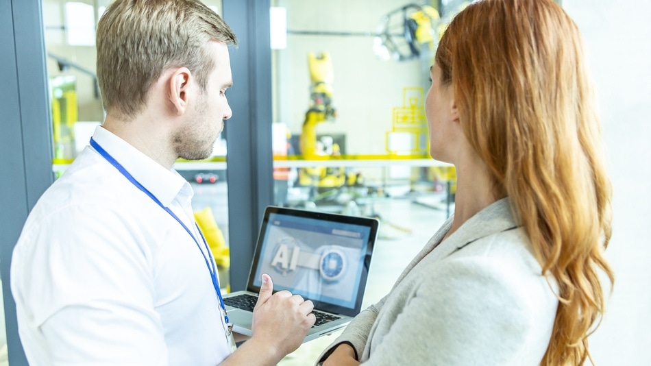 Técnicos mirando una tablet con brazos de robot en una sala