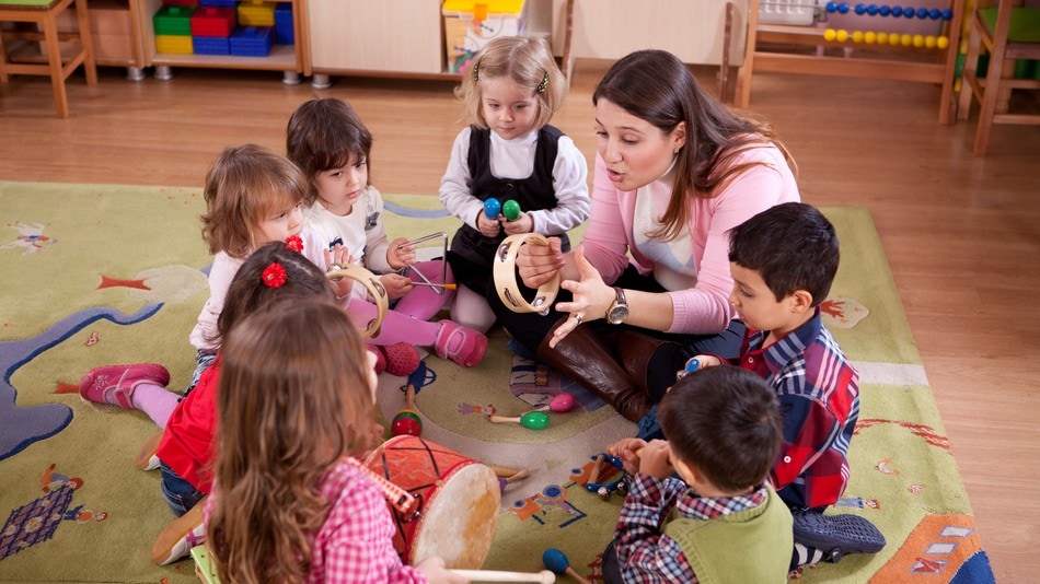 Profesora de música rodeada de niños de educación infantil