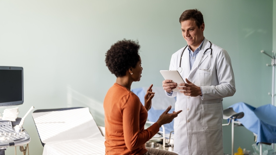 médico conversa con una paciente mientras mira los resultados de sus pruebas en su tableta digital