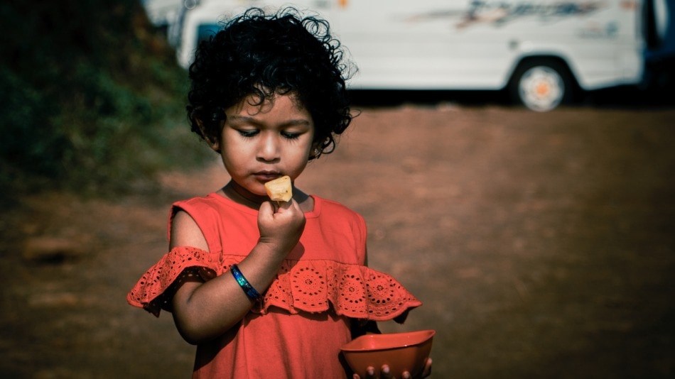 Niña comiendo fruta, sosteniendo un tazón en la mano