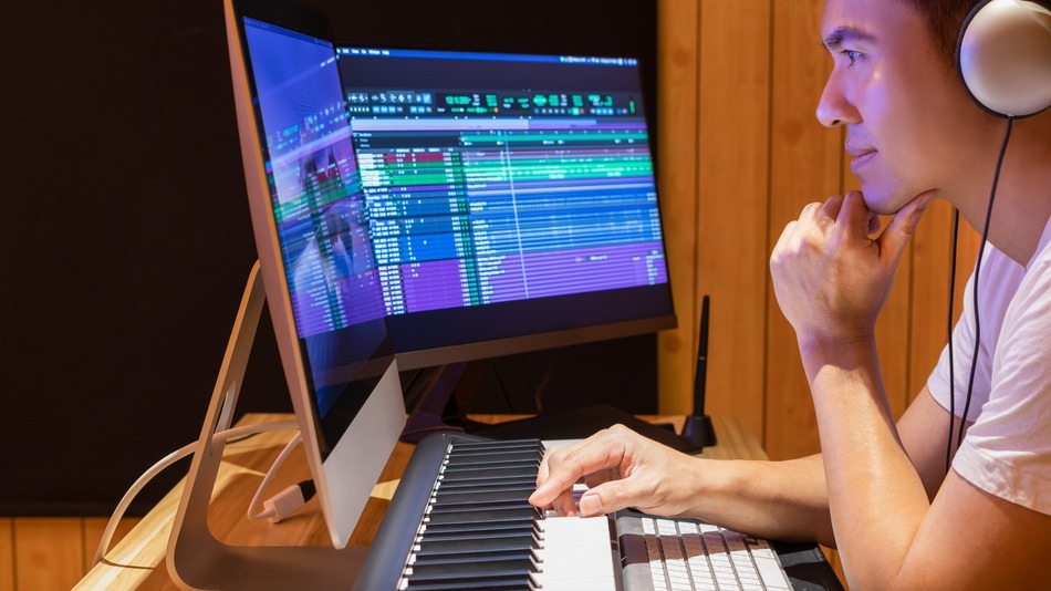 Productor de música asiática arreglando una canción en teclado midi
