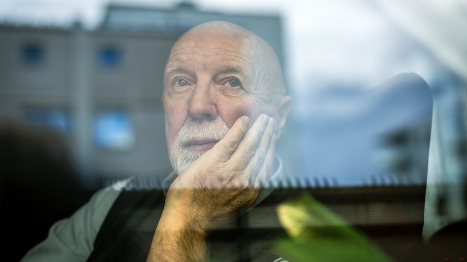 Retrato de un anciano pensativo mirando a través de la ventana