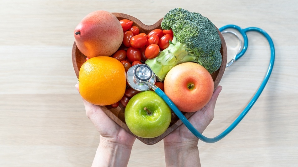 Frutas y verduras en un plato conforma de corazón y un fonendoscopio encima