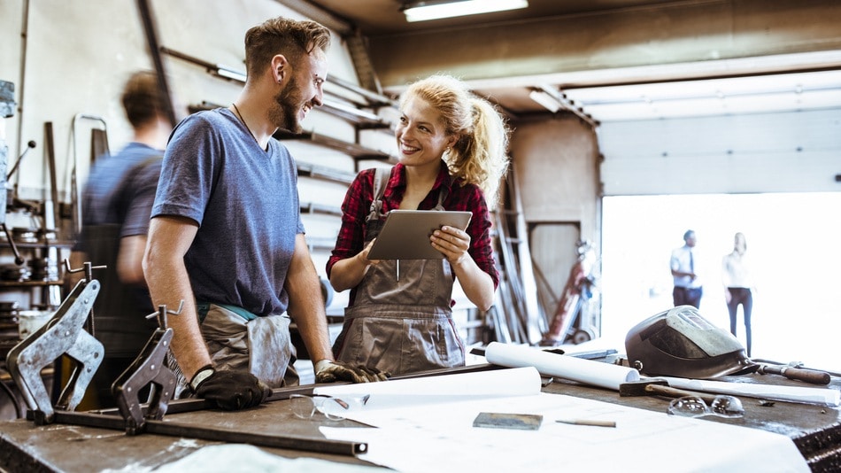 Hombre y mujer conversan alrededor de una mesa en un taller de producción