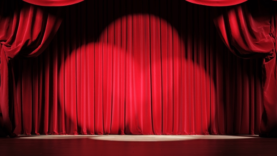 Puesta en escena de un teatro con cortinas de terciopelo rojo y focos