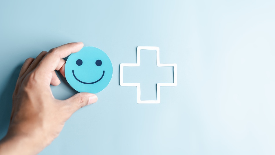 Manos sosteniendo un icono de cara azul con una sonrisa como concepto de satisfacción del paciente