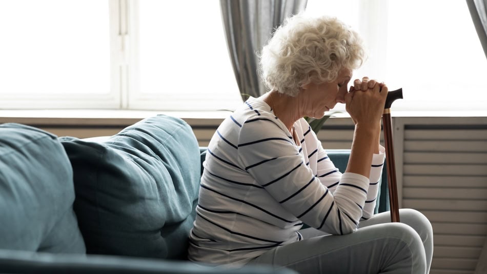 Trastorno de conducta en personas mayores mujer mayor sentada con un bastón en sus manos apoyando la cabeza