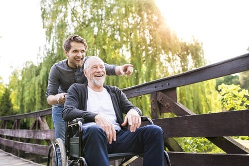 Joven de paseo con un anciano en silla de ruedas