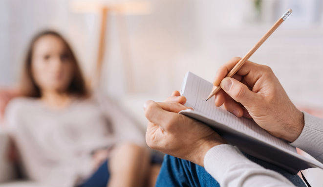 Mujer hablando con un psicólogo que apunta en un cuaderno