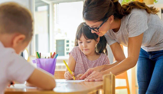 Profesora ayudando a una niña en clase. 