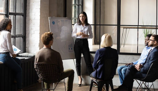 Liderazgo en la empresa. Mujer explica a un grupo de profesionales. 