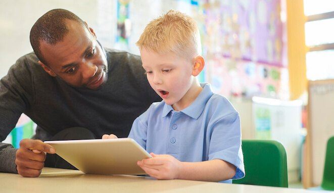 Profesor ayuda a un niño a leer. 