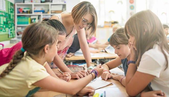 Actos del habla. Profesora ayuda en clase a niños. 