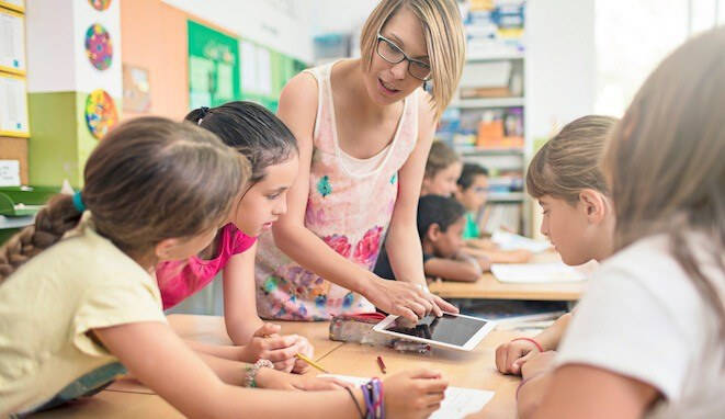 Redes sociales en el aula. Profesora con tablet enseña a alumnos. 