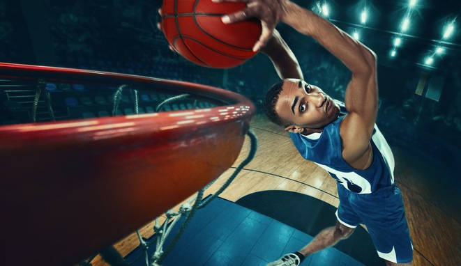 Jugador de baloncesto negro hace un mate hacia atrás. 