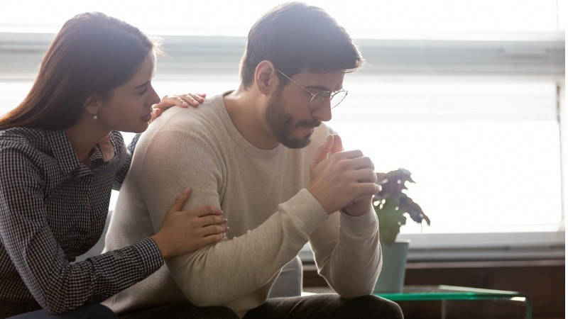 Psicología Emocional; una mujer consuela a un hombre triste en el sofa