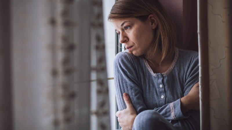 atención de las personas en situación de dependencia; mujer con depresión mirando por la ventana