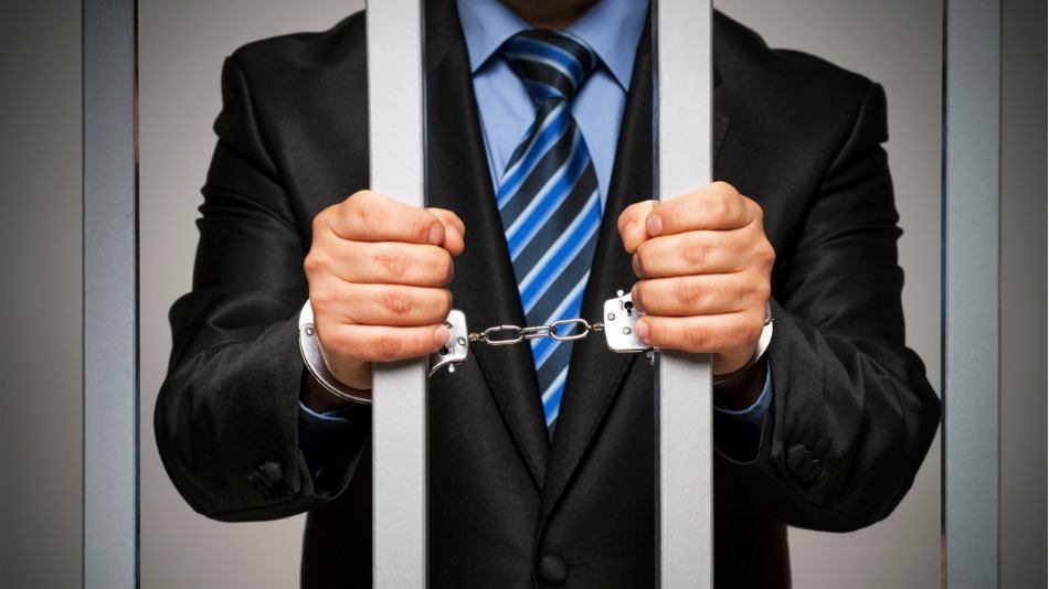 asociación diferencial criminología; un empresario en traje y corbata preso esposado