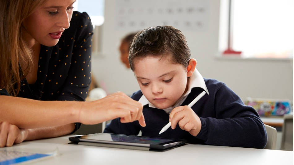 TIC en Educación Especial; una profesora trabaja con un niño con síndrome de Down con tablet