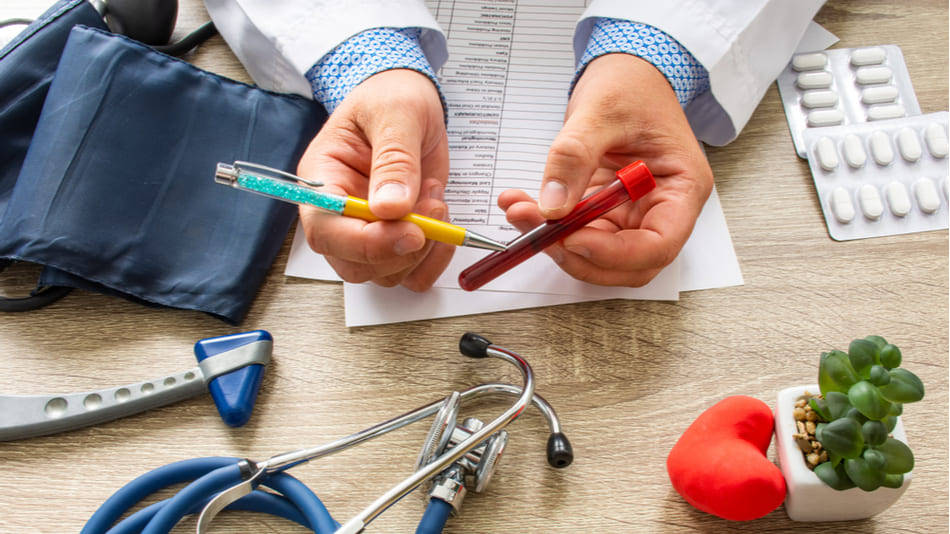 Médico señalando una muestra de sangre con boli en su escritorio