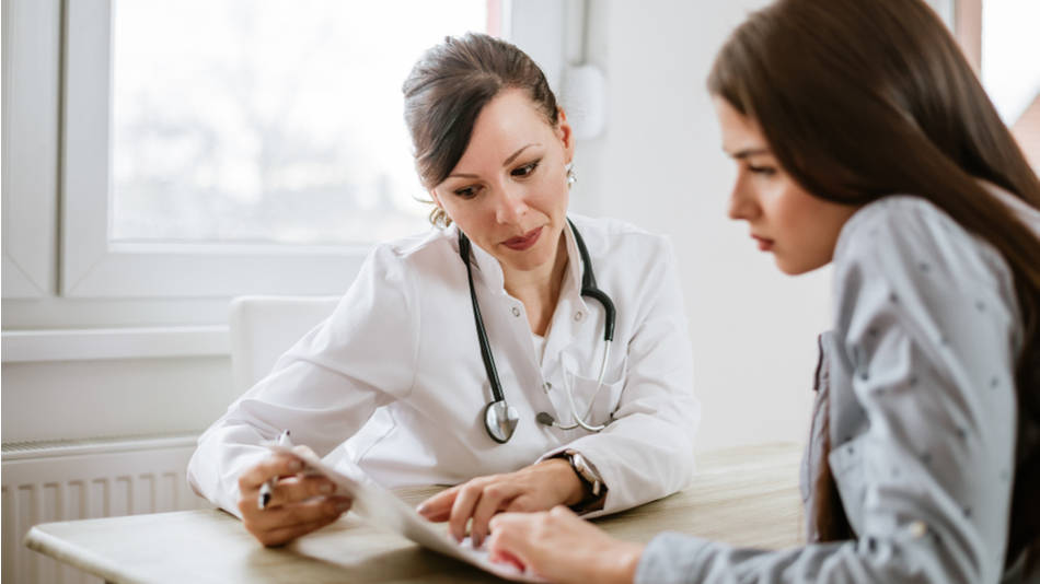 Médica y paciente revisando papeles juntas