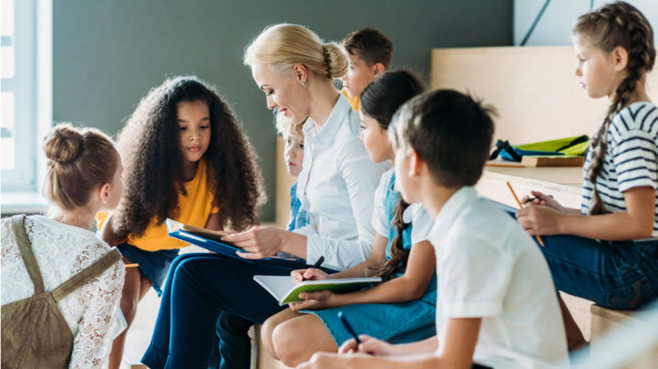 Didáctica de la Lengua en Educación Infantil y Primaria; una profesora rodeada por alumnos con libros y cuadernos para apuntar; discusión de libros