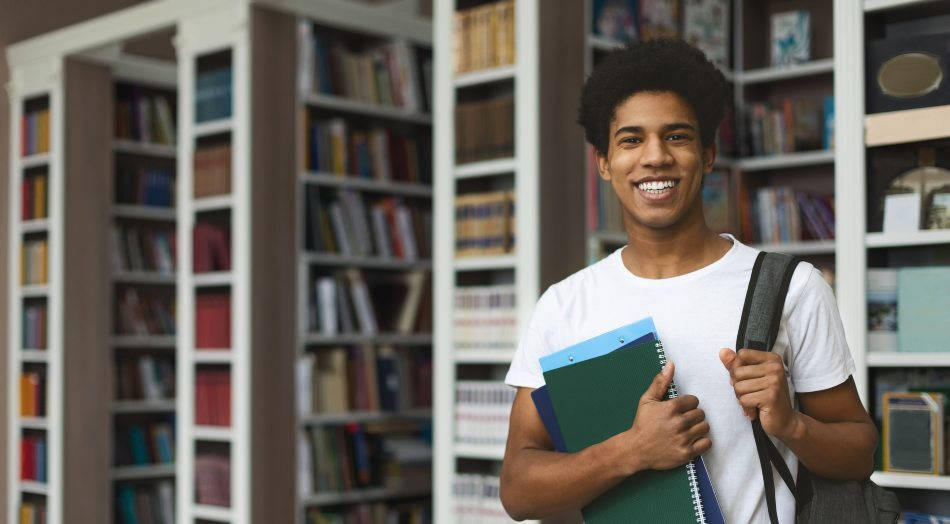 Cómo hacer un cambio de grado universitario - estudiante sonriente en biblioteca